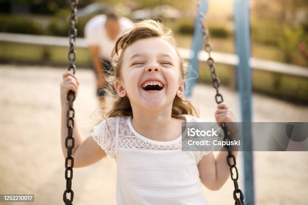 Chica Sonriente Jugando En El Columpio Foto de stock y más banco de imágenes de Niño - Niño, Felicidad, Jugar