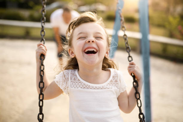 smiling girl playing on the swing - kid photo imagens e fotografias de stock