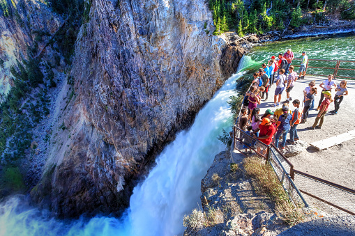 Visitors stand at the Brink of Lower Falls at Yellowstone National Park to watch rushing waters from the Yellowstone River falling into the Grand Canyon of the Yellowstone.