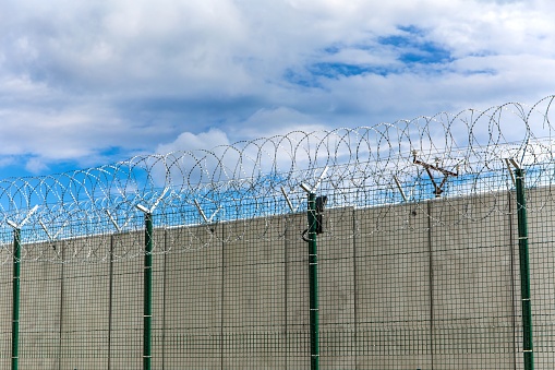 Barbed wire and concrete wall. Military base. State border. Prison wall. Security concept. Safety device.