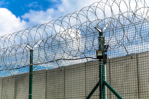 Barbed wire and concrete wall. Military base. State border. Prison wall. Security concept. Safety device.