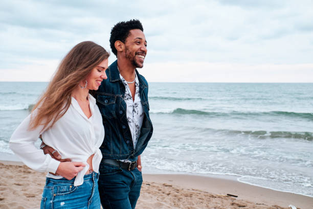 istock young interracial couple at the beach taking a walk 1252270053