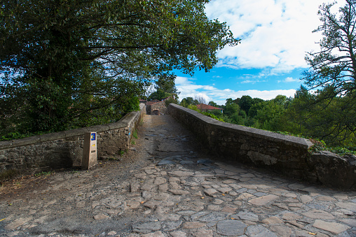 Signpost of the Camino de Santiago as it passes through the medieval bridge of Furelos in Galicia (Spain)\