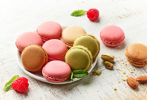 plate of various macaroons on rustic white wooden table