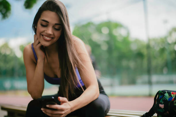 istock Young athlete woman sitting on bench and using the phone. 1252271462