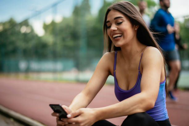 istock Young athlete woman sitting on bench and using the phone. 1252271463