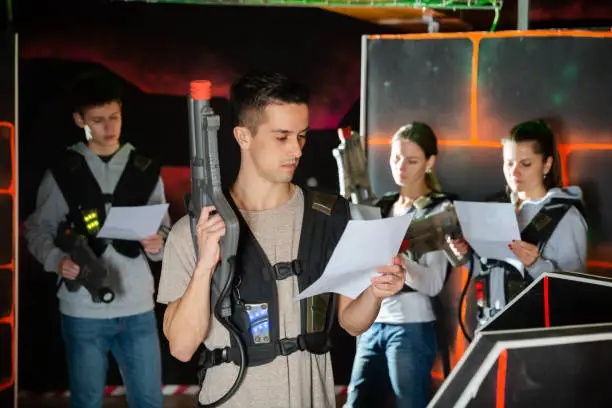 Photo of Young man reading rules before playing lasertag