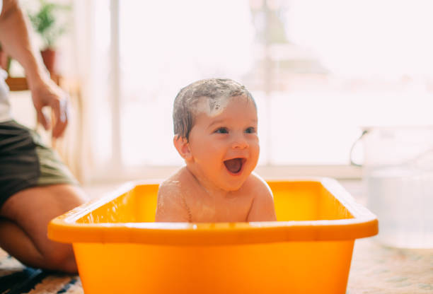 bebé lindo jugando en una bañera - bebe bañandose fotografías e imágenes de stock