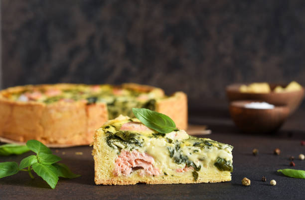 quiche (pie) with salmon, spinach and soft cheese on a dark concrete background. slice quiche. - baked breakfast cabbage cake imagens e fotografias de stock