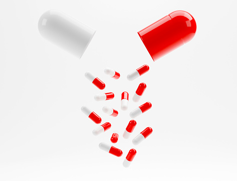 Open red white drug capsule isolated on white background. Many capsules drop on the ground and stay on the different positions. Medical and drug concept. 3D rendering.