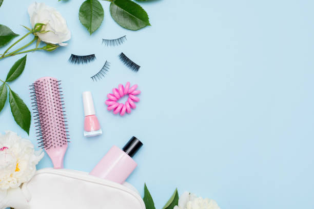 top view of set of make up and skin care products spilling out of cosmetics bag on blue background with white flowers and copy space. beauty concept. - pampering nail polish make up spilling imagens e fotografias de stock