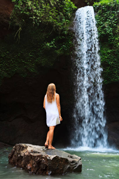 istock Woman stand under waterfall 1252298008
