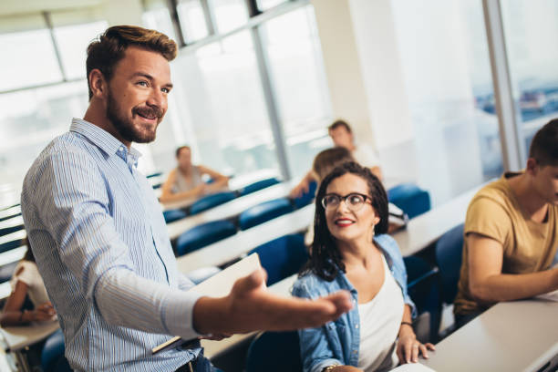 istock Group of smiling students and teacher with notebook in classroom 1252300011