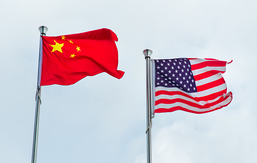 Flags of China and USA, United States of America on two poles flying on the wind with copy space