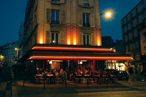 People eating outside of restaurant at night in Paris , no model release for the crowd of 12+ persons