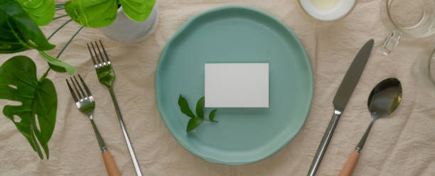 istock Dinning set with turquoise ceramic plate with white place card, silverware and decoration on dinning table with tablecloth 1252320377