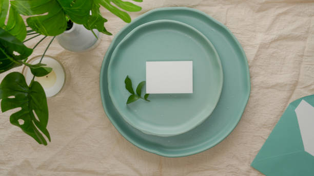Dinning set with turquoise ceramic plates, greeting card and decoration on dinning table with tablecloth
