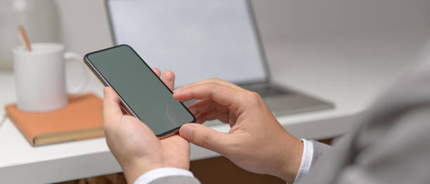 istock Male entrepreneur hands using  mock-up smartphone while sitting at white office desk 1252320414
