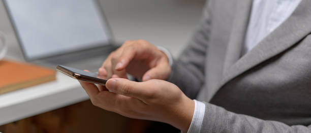 istock Side view of male entrepreneur hands using smartphone while sitting at white office desk 1252320477