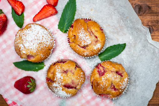 Homemade strawberry muffin desserts on a baking paper with mint leafs