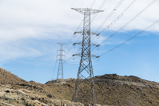a very long and tall electric supply chain of  tall metal towers on the top of dried mountains