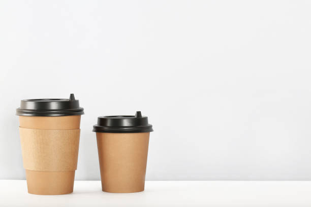 istock Craft paper coffee cups on a white table near light wall background 1252324267