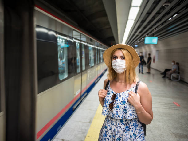 Young beautiful woman waiting for train during epidemic stock photo