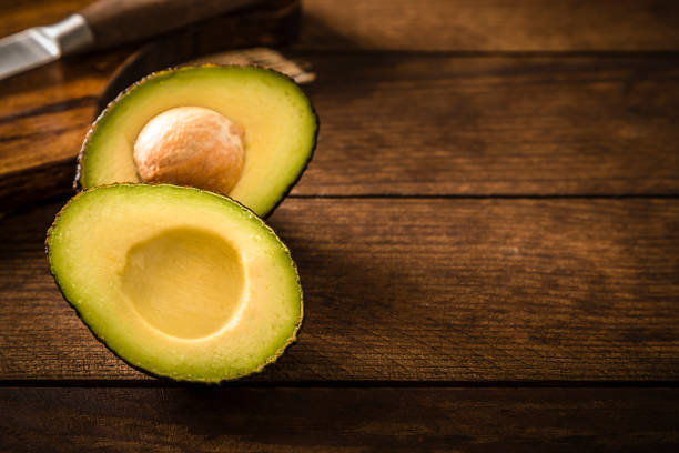 istock Sliced avocado with a kitchen knife on a rustic wooden table 1252340635