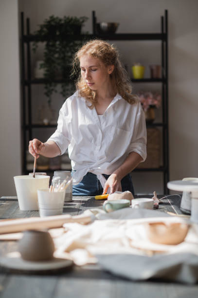 istock Female potter making ceramic dishes at her studio. Working process of glazing ceramic bowl 1252340726