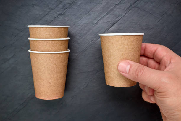 istock Person holding a recyclable cardboard cup on a black slate background 1252347095