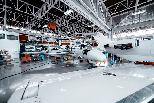 Two small private planes in a maintenance hangar.