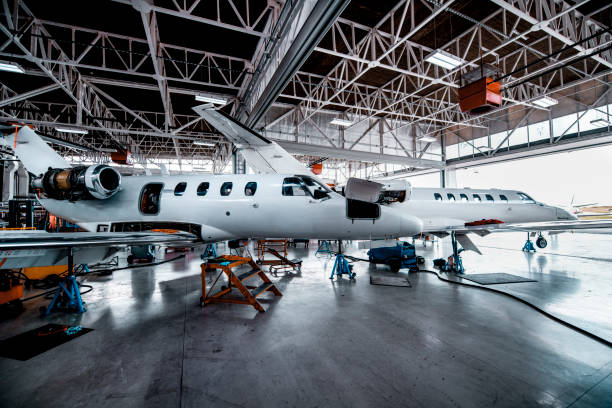 Two small private planes in a maintenance hangar Two private jets waiting for maintenance in a repair hangar of an airport. private jet plane stock pictures, royalty-free photos & images