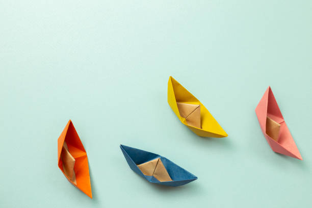 istock Colorful paper ships on blue background. ships heading for the same destination. Business, success, competition, goal concept 1252358699