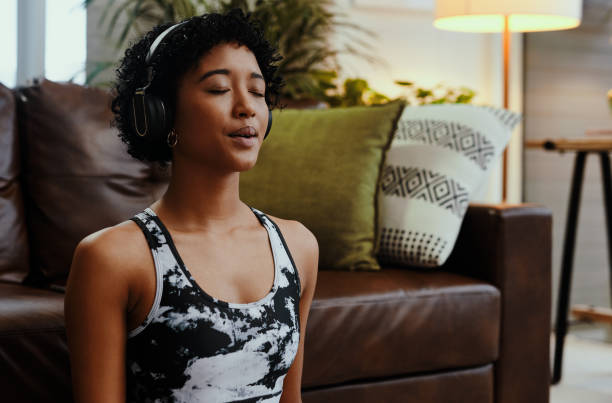 A quiet mind hears a lot Shot of a young woman listening to music while meditating at home breathing exercise stock pictures, royalty-free photos & images