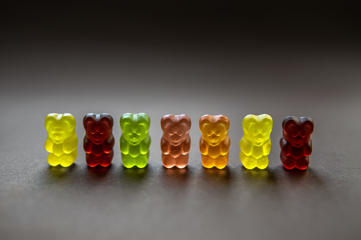 Collection of back-lit multicolored gummy bears on a neutral background. Shallow depth of field.