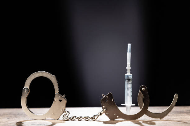 istock Handcuffs and syringe, addictive concept, wooden background 1252364084