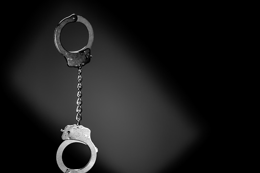 Handcuffs on black background. The scene is situated in controlled studio environment in front of black background. Photo is taken with SONY AIII camera.