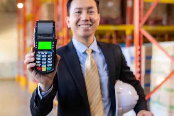 Photo of Businessman hold credit card reader in warehouse