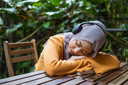 Young asian girl taking a nap after reading book outdoor