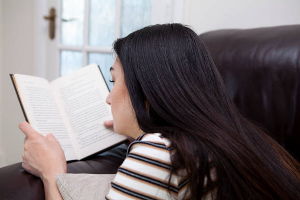 istock Young woman lying on a sofa and reading a book 1252374483