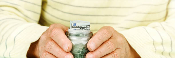 istock man hands hug jar with hundred dollar banknotes closeup 1252380003