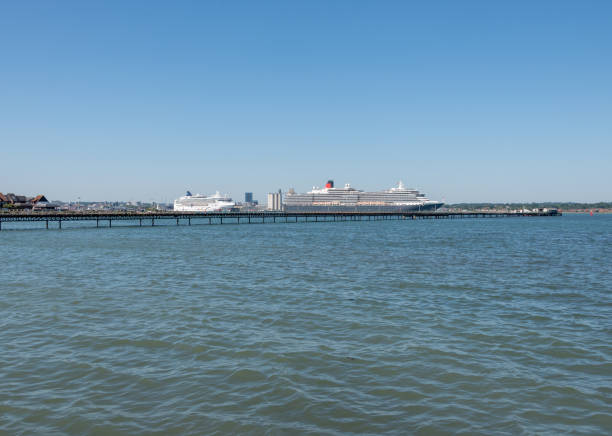 Hythe, UK. Wednesday 35 June 2020. Norwegian Star and MS Queen Victoria in Southampton Docks, with Hythe Pier in the foreground.