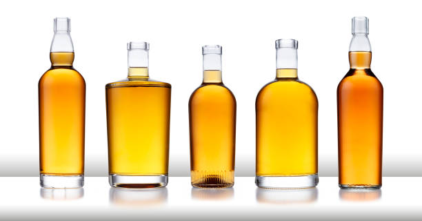 un bar blanc avec une rangée de bouteilles pleines de whisky doré, sans étiquette ni marque, isolés sur le blanc - amber bottle photos et images de collection