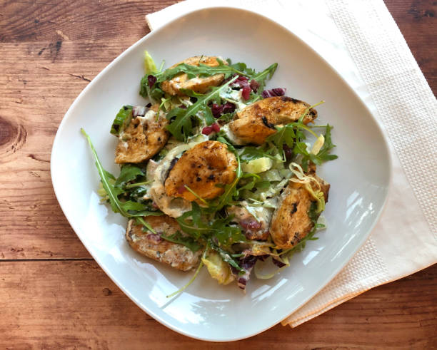 istock Grilled chicken fillets strip on mixed greens salad. 1252383567