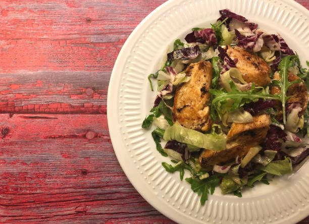 istock Grilled chicken fillets strip on mixed greens salad. 1252383571