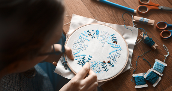 Woman sewing on grey fabric with thimble and needle, closeup