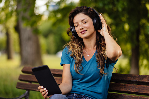 Young woman enjoying music through the headphones in the park