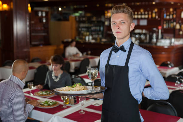 istock Waiter with serving tray meeting guests 1252394439