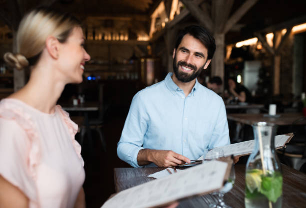 istock Happy couple sitting indoors in restaurant, looking at menu. 1252394533