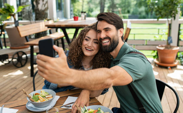 istock Happy couple sitting outdoors on terrace restaurant, taking selfie. 1252394556